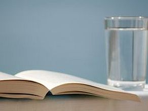 aufgeschlagenes Buch neben Wasserglas