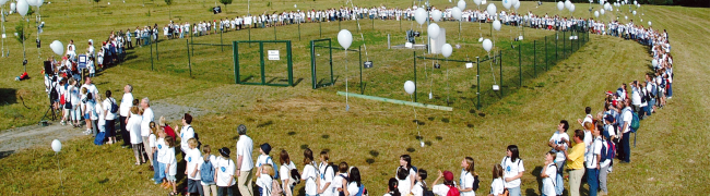Viele Kinder stehen im Kreis um eine Wasserfassung und lassen Luftballons steigen.