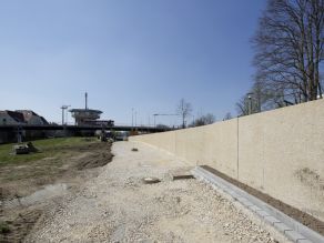 Entlang einer Hochwasserschutzmauer wird der Untergrund für einen neuen Geh- und Radweg vorbereitet.