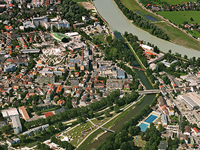 Luftaufnahme der Stadt Rosenheim mit dem Mangfallpark Süd zwischen Mangfall und Hammerbach im Vordergrund und dem Zusammenfluss der Mangfall mit dem Inn im Hintergrund.