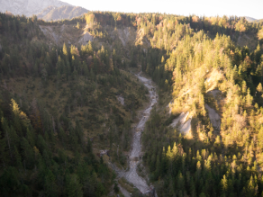 Blick auf ein Flusstal in einer Bergflanke mit zahlreichen Wildbachsperren.