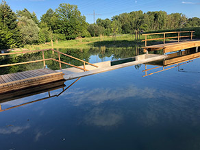 Teich mit einem durch Holzstege begehbaren Einbau aus Beton mit der Möglichkeit durch eine Scheibe unter das Wasser zu schauen.