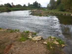 An einer neuen Flussschleife kommt es im Bereich einer Engstelle zu einer Änderung im Strömungsverhalten und das Wasser fließt etwas turbulent weiter. Die Ufer sind abgeflacht und nur spärlich bewachsen.