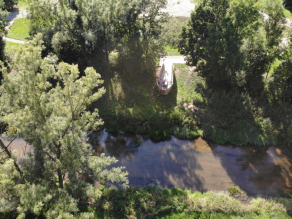 Luftaufnahme eines Flusses, an dessen Ufer sich eine Erlebnisplattform befindet.