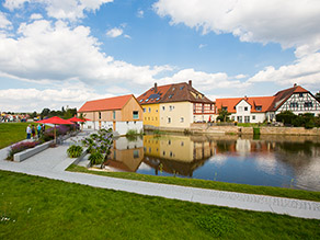 Das Mühlengebäude (Alte Säge) am alten Flusslauf der Wörnitz. Jetzt ein See mit Sitzstufen und Gehweg entlang des Wassers.