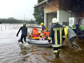 Schlauchbooteinsatz von Feuerwehr und Wasserwacht an einem landwirtschaftlichen Hof.